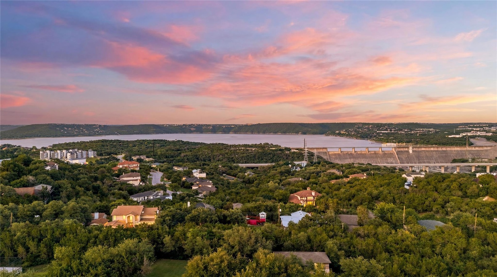 Sunset aerial of Lake Travis, Mansfield Dam, and Hill Country homes near Apache Shores